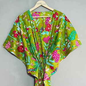 Peut inclure: Une kaftan verte &agrave; imprim&eacute; floral avec des fleurs roses, bleues et blanches, des oiseaux et d'autres motifs. La kaftan a un col en V et des manches courtes. Elle est nou&eacute;e &agrave; la taille avec un cordon.