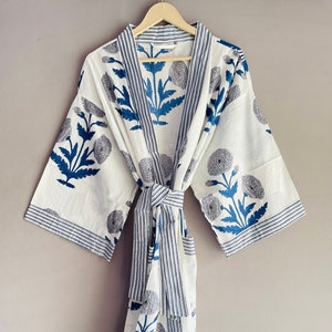 May include: White cotton robe with a blue floral print and blue and white striped trim. The robe has a tie belt and a pocket.