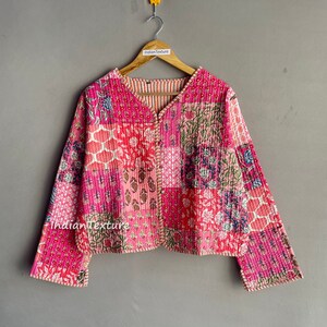 May include: A pink quilted jacket with a floral patchwork design. The jacket has a V-neck and long sleeves. The fabric is soft and comfortable.