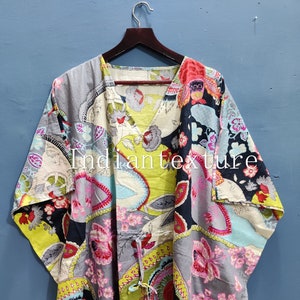 Puede incluir: Un caftán estampado con cuello en V y cintura con cordón. La tela presenta un diseño de patchwork con motivos florales y paisley en tonos grises, rosas, amarillos y azules. El texto "Indiantexture" es visible en la prenda.