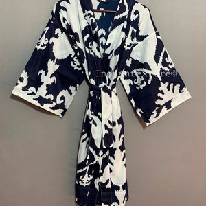 May include: A navy blue and white cotton kimono robe with a large abstract floral print. The robe has a tie belt and long sleeves.