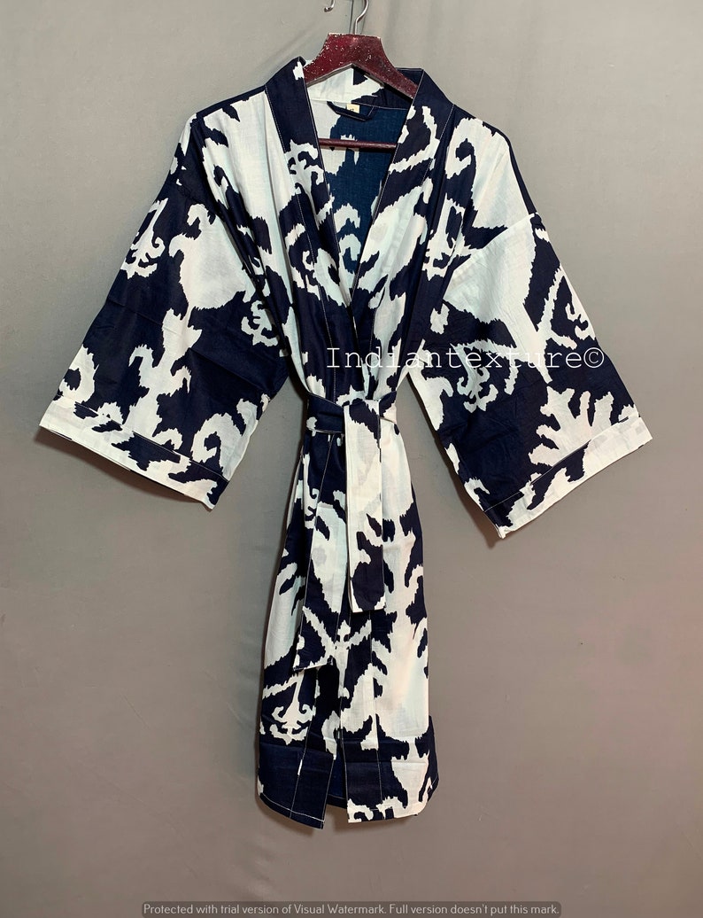 May include: A navy blue and white cotton kimono robe with a large abstract floral print. The robe has a tie belt and long sleeves.