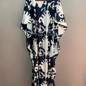 May include: A long, white and navy blue kaftan with a large, abstract print. The kaftan has a V-neck and short sleeves. The fabric is lightweight and flowy. The text "Indiantexture" is visible on the garment.