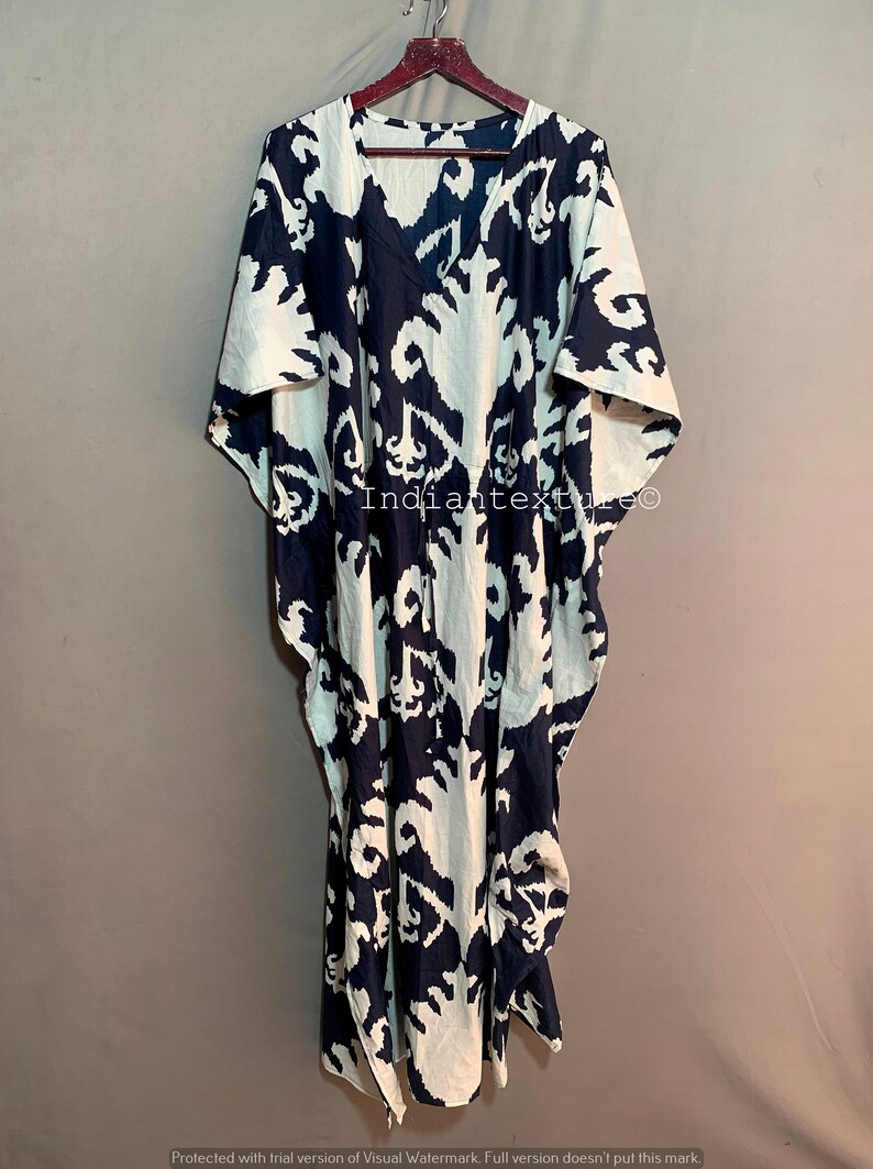 May include: A long, white and navy blue kaftan with a large, abstract print. The kaftan has a V-neck and short sleeves. The fabric is lightweight and flowy. The text "Indiantexture" is visible on the garment.