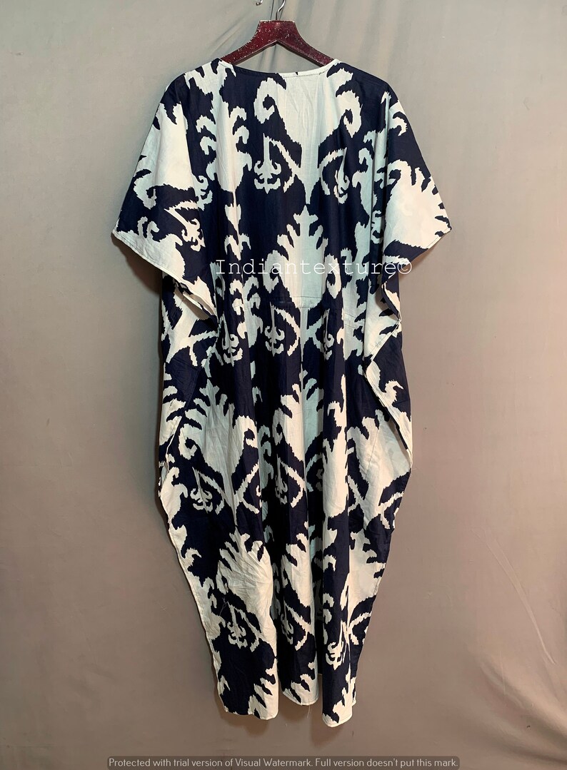 May include: A long, flowing white and navy blue kaftan with a geometric pattern. The kaftan has a wide, round neckline and short sleeves.