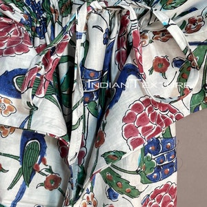 May include: White fabric garment with a floral and bird pattern in red, blue, green, and brown. The garment has a tie closure and the text "INDIAN TEXTURE" is visible.