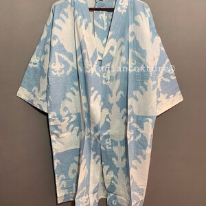 K&ouml;nnte beinhalten: Ein hellblauer Kimono mit einem wei&szlig;en und hellblauen Ikat-Muster. Der Kimono hat einen V-Ausschnitt und kurze &Auml;rmel. Der Text "Indiantexture" ist auf der Vorderseite des Kimonos sichtbar.