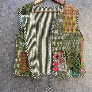 May include: A green quilted vest with a floral print and a striped lining. The vest has a V-neck and a tie closure.