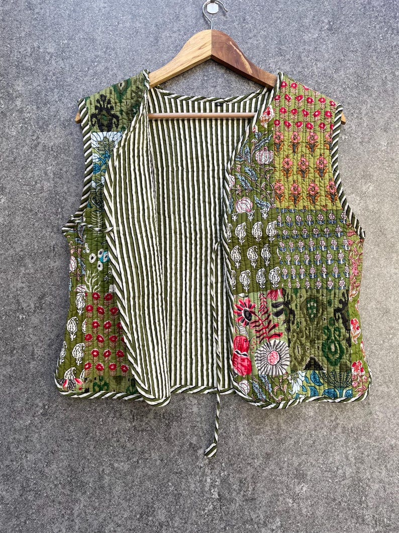 May include: A green quilted vest with a floral print and a striped lining. The vest has a V-neck and a tie closure.
