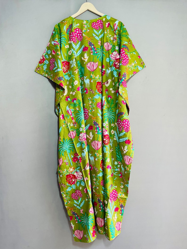 Peut inclure: Une longue kaftan verte &agrave; imprim&eacute; floral avec des fleurs roses, rouges et bleues, des oiseaux et des cerfs. La kaftan a une silhouette ample et fluide et des manches courtes.