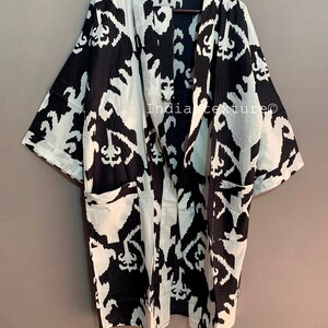 May include: Black and white kimono robe with a geometric pattern. The robe has a long, flowing silhouette and a wide, open collar. It is made of a lightweight fabric and has a relaxed fit.