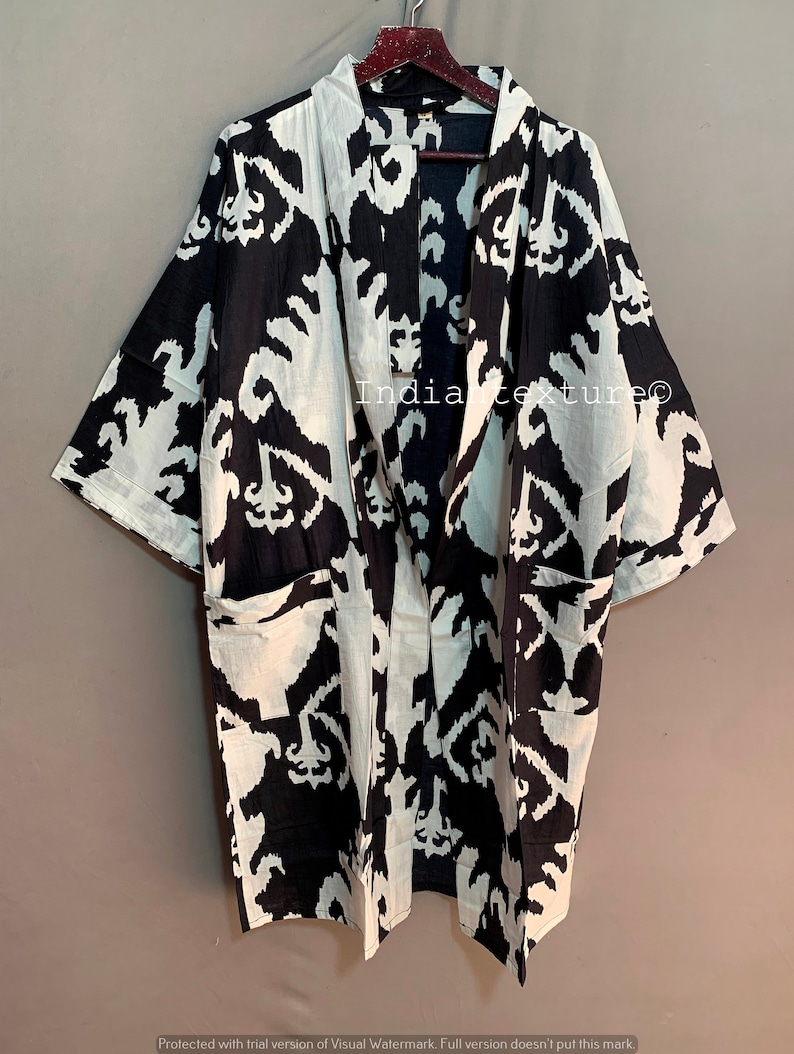 May include: Black and white kimono robe with a geometric pattern. The robe has a long, flowing silhouette and a wide, open collar. It is made of a lightweight fabric and has a relaxed fit.