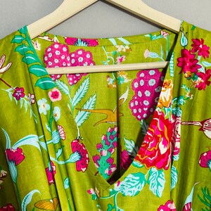 Peut inclure: Un tissu en coton vert avec un imprim&eacute; floral compos&eacute; de fleurs roses, rouges et blanches, de feuilles vertes et d'oiseaux. Le tissu est sur un cintre en bois avec le texte "INDIAN TEXTURE" &eacute;crit dessus.