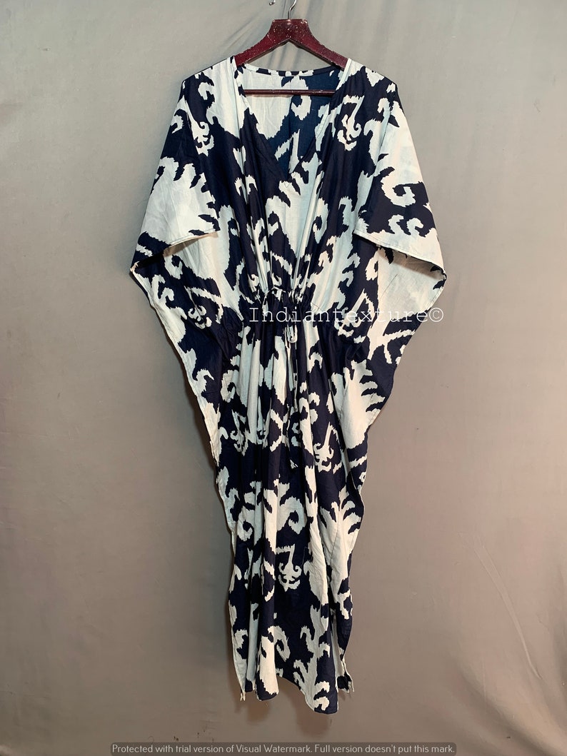 May include: A white and navy blue kaftan with a geometric pattern. The kaftan has a V-neck and a drawstring waist.