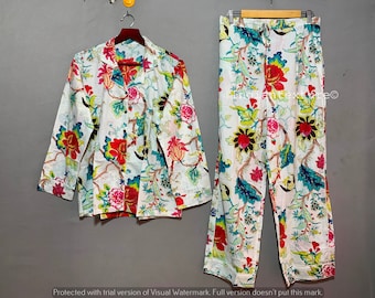 May include: A white pajama set with a floral print in shades of pink, red, blue, and green. The set includes a long-sleeved shirt and pants.