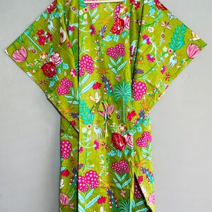 Peut inclure: Un kimono en coton vert avec un imprim&eacute; floral compos&eacute; de fleurs roses, rouges, bleues et blanches, d'oiseaux et de cerfs. Le kimono a un col en V et des manches larges. Le texte "INDIAN TEXTURE" est imprim&eacute; sur le cintre.