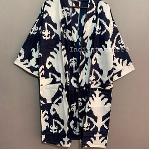 May include: A long, black and white kimono with an ikat pattern. The kimono has a wide collar and long sleeves. The fabric is soft and flowing.
