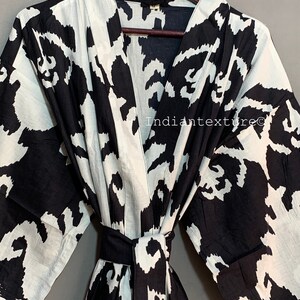 May include: Black and white patterned cotton robe with a long sleeve and a sash tie. The robe has a large abstract print.