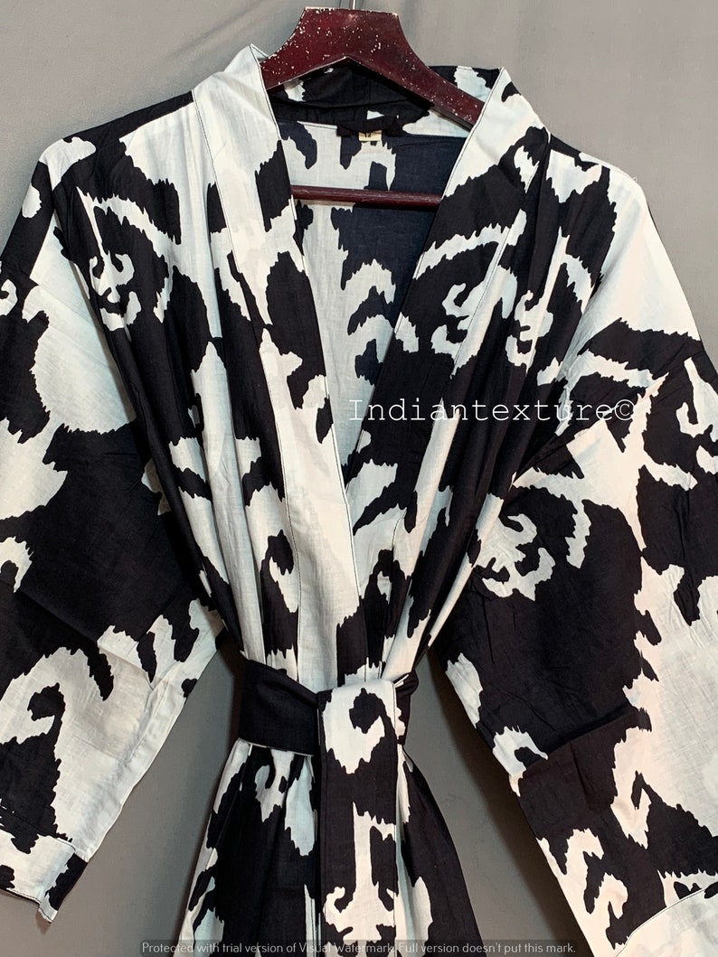 May include: Black and white patterned cotton robe with a long sleeve and a sash tie. The robe has a large abstract print.