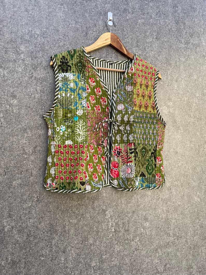 May include: A green quilted vest with a floral print and a tie closure. The vest is made of cotton and has a patchwork design.