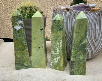 May include: Four green serpentine stone points with a pointed tip. The stones have a marbled pattern with white and black accents.
