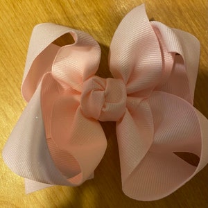 May include: A large pink sparkly hair bow with a centre knot.