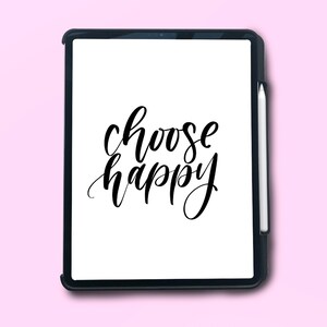 Puede incluir: Una tableta negra con una pantalla blanca que muestra el texto "choose happy" en caligraf&iacute;a negra. La tableta est&aacute; sobre un fondo rosa.