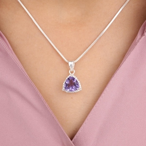 Op de afbeelding: Een zilveren ketting met een driehoekige amethist hanger.