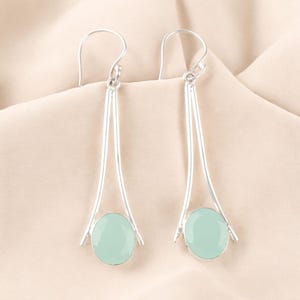 Può includere: Un paio di orecchini pendenti in argento con pietre ovali di colore blu chiaro.