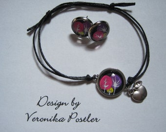 May include: A black string bracelet with a silver charm featuring a colorful tree design. The bracelet also includes a silver apple charm and a pair of matching earrings with the same tree design.