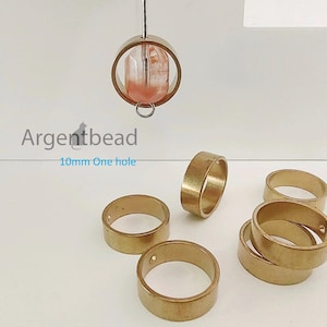 May include: Ten 10mm brass rings, each with one hole. The rings are stacked and scattered on a white surface. Argentbead 10mm One hole.