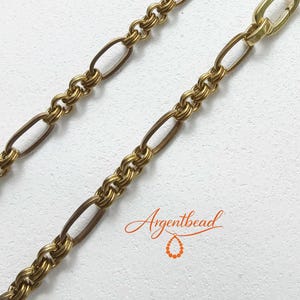 May include: A gold-toned metal chain necklace featuring alternating elongated oval links and sections of tightly coiled, textured wire rings. The chain includes a smooth, polished oval clasp connector. The text Argentbead is visible.
