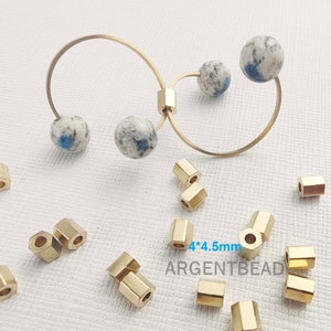 May include: Gold-toned metal hoops with blue and white speckled stone beads. The hoops are 4 inches in diameter. There are also 12 gold-toned metal spacer beads, each measuring 4mm by 4.5mm.