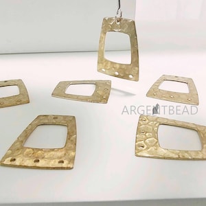 Pode incluir: Seis pingentes de metal dourado com forma retangular e um recorte no centro. Os pingentes têm uma textura martelada e são perfeitos para a criação de joias.
