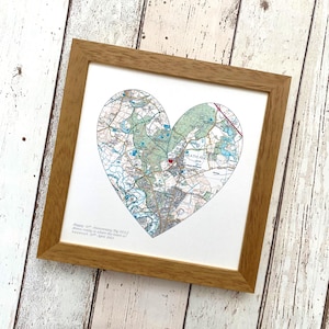 May include: A framed print of a map of a town with a heart-shaped outline. The map is in shades of blue, green, and brown. The text below the map reads "Happy 12th Anniversary Big Will.  This map is where the magic of our love story began.  August 20th 2012."