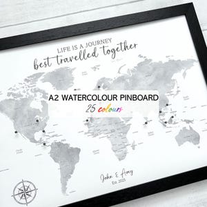 May include: A framed A2 watercolor pinboard map with a black frame. The map is in grayscale with pins marking locations. Text includes "LIFE IS A JOURNEY best travelled together", "A2 WATERCOLOUR PINBOARD", "25 colours", and a personalized name and date.