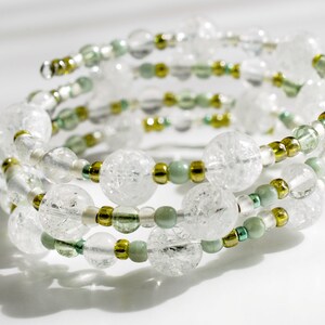 May include: A white and green beaded bracelet with a spiral design. The beads are made of glass and have a frosted finish.
