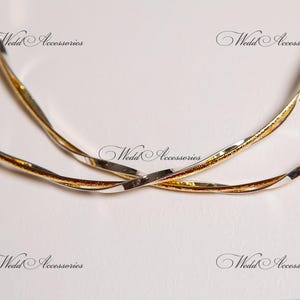 May include: Two intertwined silver and gold rings, a wedding accessory.
