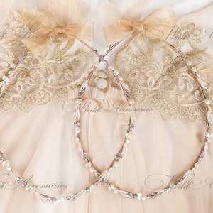 May include: Two delicate wedding headbands with pearl and crystal accents. Each headband features a thin, flexible wire base adorned with small pearls, crystals, and subtle purple beads. The headbands are topped with a sheer, light brown bow.