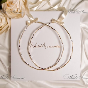 May include: Two gold wedding rings, intertwined, on a white background. The rings are made of a braided metal design.
