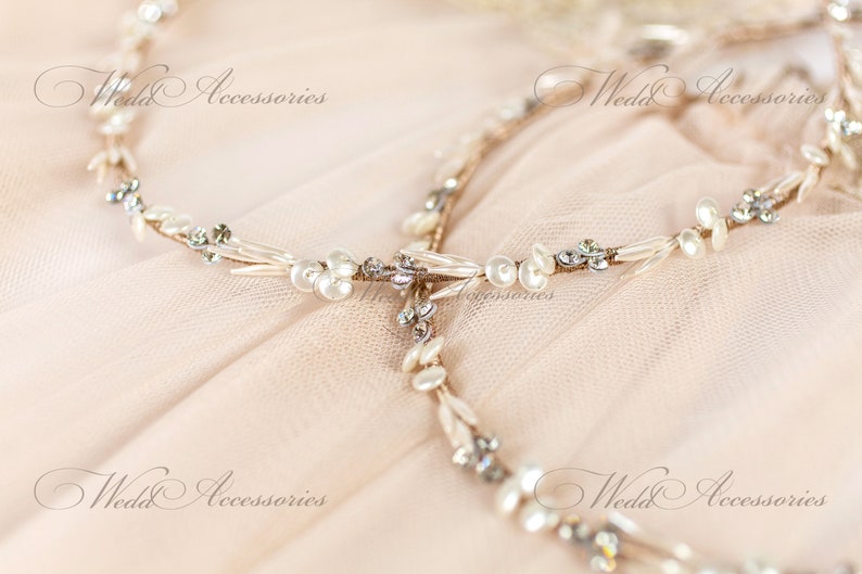 May include: A delicate bridal headpiece with a floral design. The headpiece features small white pearls, clear crystals, and a gold-toned wire base. The text "Wedd Accessories" is visible in the image.