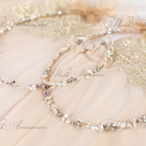 May include: Two delicate bridal headbands with pearl and crystal accents. The headbands are intertwined, resting on a soft, peach-colored fabric. The words "Wedd Accessories" are visible in the image.