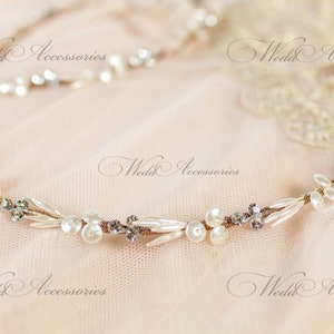 May include: A delicate bridal headband featuring faux pearls, clear crystals, and small, elongated beads. The design is accented with a thin, gold-toned wire. The text "Wedd Accessories" is visible.