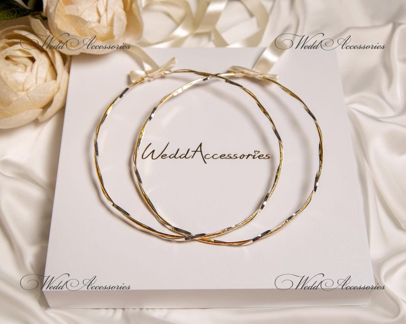 May include: Two gold and silver intertwined wedding rings on a white background. The rings are a traditional symbol of marriage and commitment.