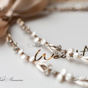 May include: Close-up of a bridal headpiece with a beige satin ribbon and delicate strands. The strands are adorned with white pearls, clear crystals, and small white disc-shaped accents. The text "Wedd Accessories" is visible.