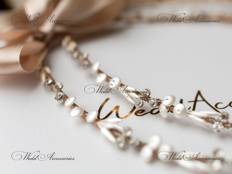 May include: Close-up of a bridal headpiece with a beige satin ribbon and delicate strands. The strands are adorned with white pearls, clear crystals, and small white disc-shaped accents. The text "Wedd Accessories" is visible.