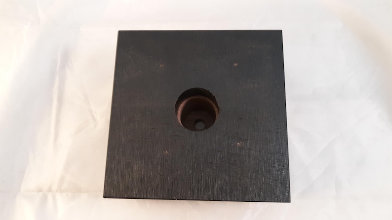 May include: A black square wooden base with a circular hole in the center. The base is made of wood with a dark stain.