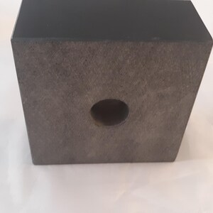 May include: A black wooden base with a round hole in the center. The base is textured and has a smooth, polished finish.