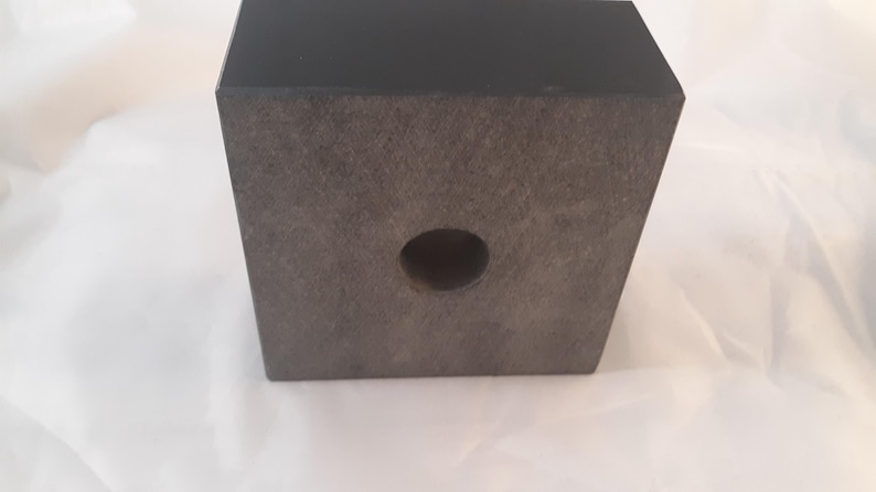 May include: A black wooden base with a round hole in the center. The base is textured and has a smooth, polished finish.
