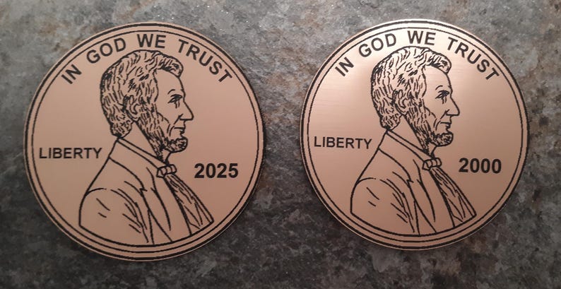 Op de afbeelding: Twee koperkleurige ronde munten met het beeld van Abraham Lincoln. De munten hebben de tekst "IN GOD WE TRUST" en "LIBERTY". E&eacute;n munt is gedateerd 2025, de andere 2000.